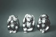 Black and white photo of three wise monkeys figurines showing the hear no evil, see no evil, speak no evil poses.