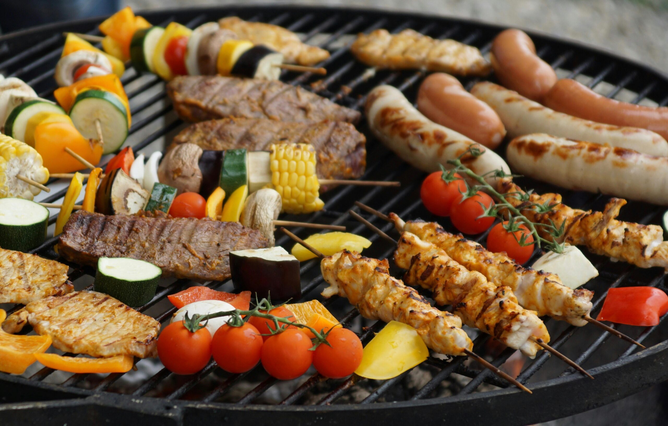 A vibrant assortment of grilled meats, sausages, and vegetables on a barbecue grill.